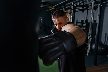 Closeup boxer with punching bag for training. A strong male fighter with boxing gloves trains on a...