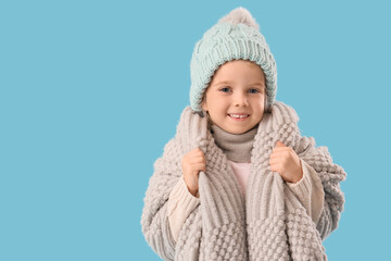 Cute little girl in winter clothes on blue background