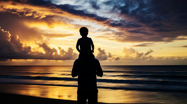 Shadow of a man on the beach with a child riding on his back, watching the sunset.
