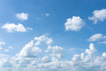 Fluffy white clouds float across a clear blue sky, creating a beautiful summer day