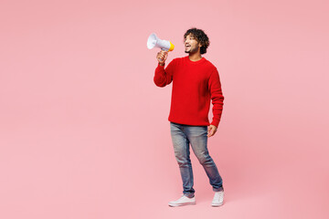 Full body young Indian man he wear red sweater casual clothes hold in hand megaphone scream...