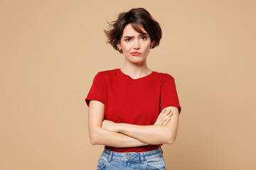 Young frowning grumpy upset dissatisfied sad woman she wear red t-shirt casual clothes hold hands...