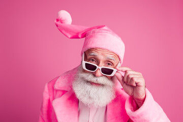 Photo of cool nice senior man wear trendy bathrobe hand hold summer eyewear look suspiciously isolated on pink color background