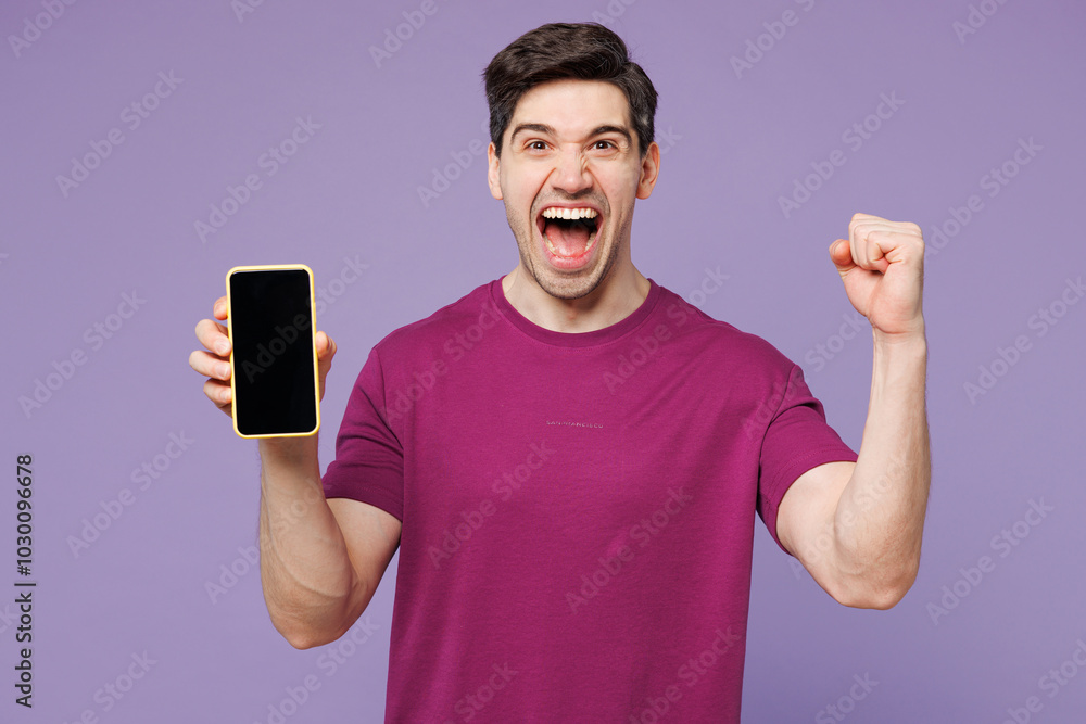 Poster Young man wear violet t-shirt casual clothes hold in hand use mobile cell phone with blank screen workspace area do winner gesture isolated on plain pastel light purple background. Lifestyle concept.