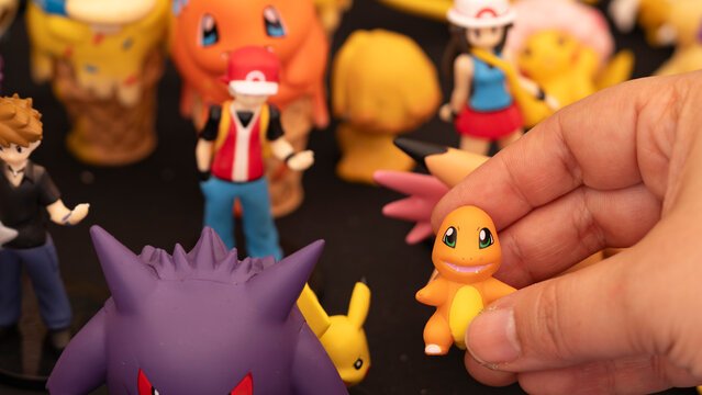 Budokan Geek Convention In GUAYAQUIL, ECUADOR - 
OCT 13, 2024 - Close-up of a hand holding a small Charmander Pok&eacute;mon figure, surrounded by other Pok&eacute;mon and trainer figurines