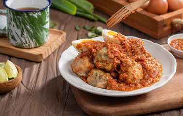 A plate of traditional siomai, a type of Indonesian steamed dumpling served with a spicy peanut sauce and accompanied by hard-boiled eggs. a hand holding a fork is lifting a piece