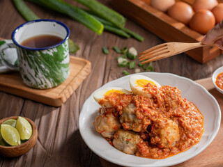 A plate of traditional siomai, a type of Indonesian steamed dumpling served with a spicy peanut sauce and accompanied by hard-boiled eggs. a hand holding a fork is lifting a piece