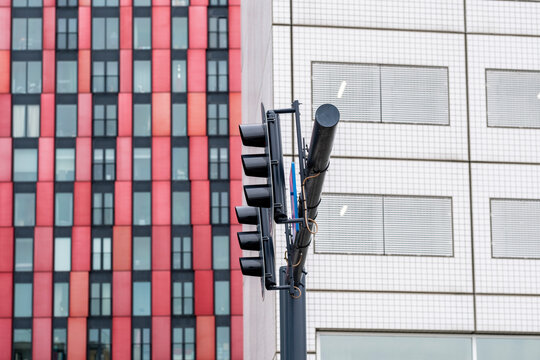 A vibrant red and black building facade stands next to a series of traffic lights in an urban setting, showcasing the lively contrast in colors and design elements.