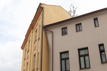 There is a large building featuring numerous windows and prominently displaying a satellite dish fixed firmly atop its roof structure