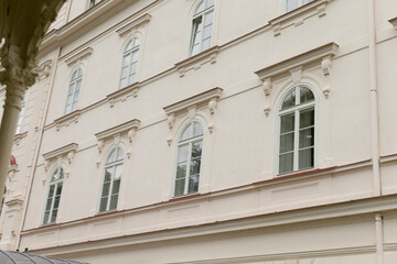 There is a large, striking white building that features numerous windows and has a beautiful tree situated in front of it