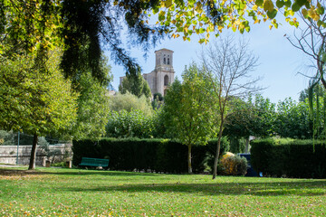 Obraz premium Paisaje otoñal con arboles y hierva y vista de la Iglesia de Pampliega, Burgos (España) vista entre árboles