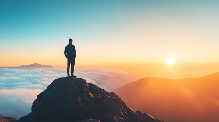 Obraz premium Silhouette of a Person Standing on a Mountain Peak at Sunset