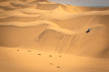 Sandwich Harbour in Namibia mit einem 4x4 Fahrzeug - ein Geländefahrzeug fährt über riesige Dünen - Abenteuer Wüste