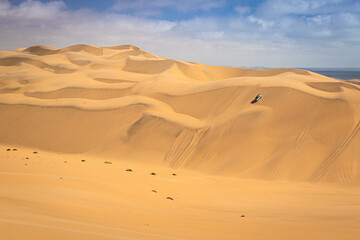 Sandwich Harbour in Namibia mit einem 4x4 Fahrzeug - ein Geländefahrzeug fährt über riesige Dünen, Wüstenfahrt in Afrika