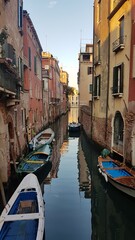 Narrow canal, old buildings and boats in Venice, Italy.