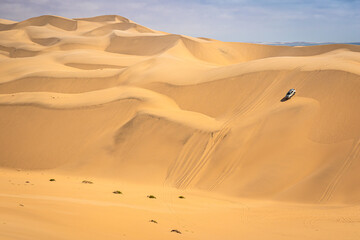 Sandwich Harbour in Namibia mit einem 4x4 Fahrzeug - ein Geländefahrzeug fährt über riesige Dünen, Wüstentour bei Walvis Bay