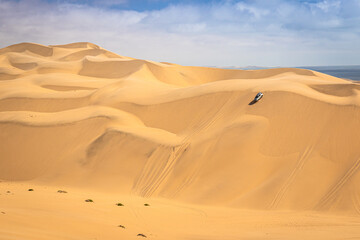 Sandwich Harbour in Namibia mit einem 4x4 Fahrzeug - ein Geländefahrzeug fährt über riesige Dünen, Offroad Abenteuer in Afrika