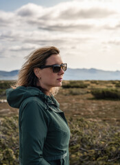 Woman in Sunglasses stands in the expansive Flatruet high fell, facing the majestic mountains, her hair blowing gently in the wind, bright glowing sunlight on her face. Enjoying the beauty of Sweden