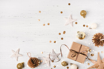 Festive Christmas background with gift box and Christmas decorations on white wooden table. Top view. Copy space for text.