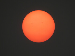 Photo of the sun on a day with a lot of smoke from the fires during the prolonged dry season. Photo of the reddish sun with details of sunspots