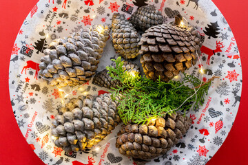Christmas and New Year decoration with fir cones and lights on red background