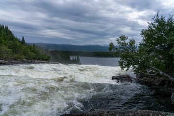 Scenic view of a river flowing through a green landscape in Taennforsen, Sweden on a cloudy day