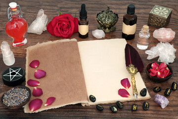 Witchcraft love potion with rose flower, magical equipment and book of spells. Romantic concept for...