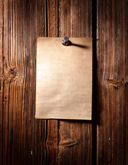Blank paper note hangs on a wooden wall with a thumbtack, creating a rustic look. Perfect for announcements, reminders, or messages. Ready for creative use