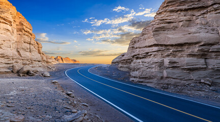 Asphalt road and Yardang landform mountain natural landscape at sunrise. road trip.