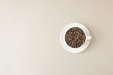 White cup with coffee beans on bright background. Minimal concept.