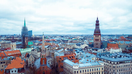 Obraz premium A panoramic view of Riga's historic skyline featuring churches, rooftops, and modern architecture under a cloudy sky