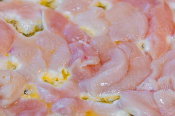 closeup full-frame background of raw chicken breast meat just starting to roast.
