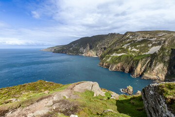 Fototapeta premium Expansive view of Slieve League cliffs in Ireland, with sheer rock faces dropping into the deep blue Atlantic, under a bright sky