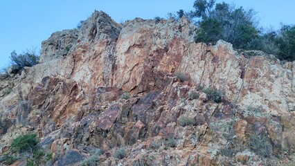 Rocky wall in Sant'Andrea, Italy, formed during road construction. Red-orange inclusions in rock...