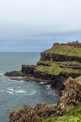 Vertical photo of the rugged cliffs at Giant Causeway with vibrant, contrasting rock layers. The...