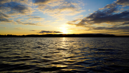 Sunset on the lake with a mirror image of the sun and sky on the water. Landscape view of the lake, calm environment. Beauty is in nature.
