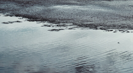 Close-up of melting spring ice on the lake shore. There are ice floes floating in the water. It's spring now, the ice is melting.	