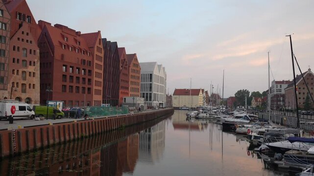 Apartments along Motlawa river in Gdansk. Canal with boats on a calm morning
