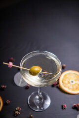 Cocktail based on martini in a glass on a thin stem, decorated with an olive