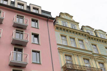 There is a pink building with multiple balconies situated right next to a green building that also has balconies adorning its facade