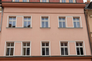 A vibrant pink building that features an abundance of windows adorning its structure, making it a visually appealing sight in the area