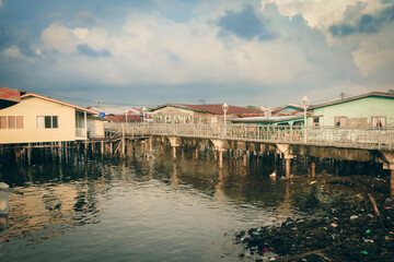 Picturesque stilt houses reflecting on water in Kota Kinabalu during a serene afternoon setting