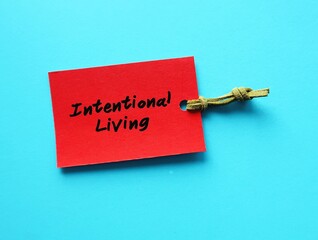 Red paper tag on blue background with handwritten words INTENTIONAL LIVING, means understanding...
