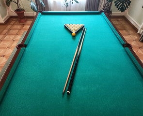 Balls with a cue lie on the green cloth of a billiard table, background. Copy space for text