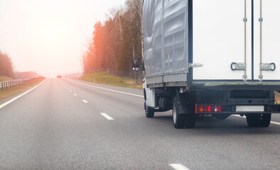 An isotherm van transports flowers along a country road in spring against the backdrop of the sun and forest. Copy space for text