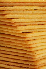 Rectangular, savory salty cheese-flavored biscuits with a golden-yellow color, neatly stacked. Perfect as a snack. Photographed on a white background.