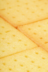 Rectangular, savory salty cheese-flavored biscuits with a golden-yellow color, neatly stacked. Perfect as a snack. Photographed on a white background.