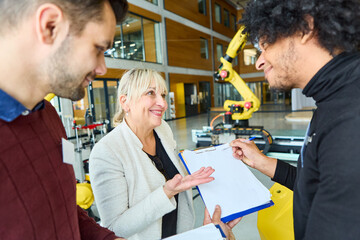 Group of engineers discussing robotics with gripper arms in industrial setting