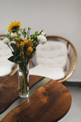 bouquet of beautiful yellow sunflower flowers in a glass vase on an old rustic wooden table. Autumn cozy home decor