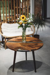 bouquet of beautiful yellow sunflower flowers in a glass vase on an old rustic wooden table. Autumn cozy home decor